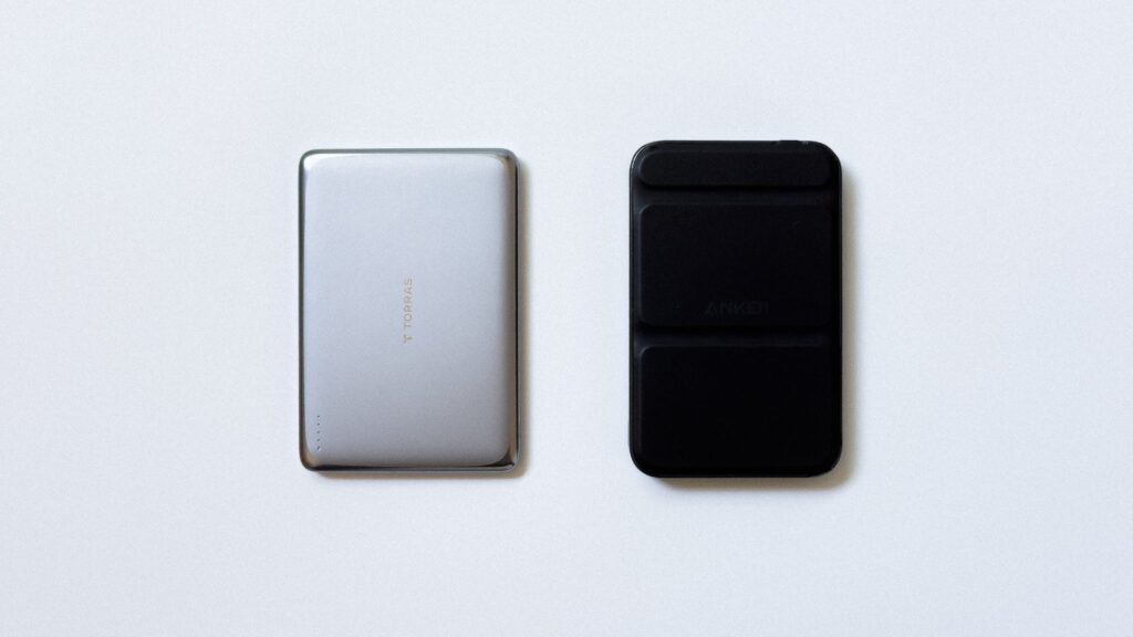 MiniMag Pro(左)と他社製モバイルバッテリー(右)を真上から並べた比較カット。スリムな金属筐体と折りたたみスタンド構造の差が一目で分かる。