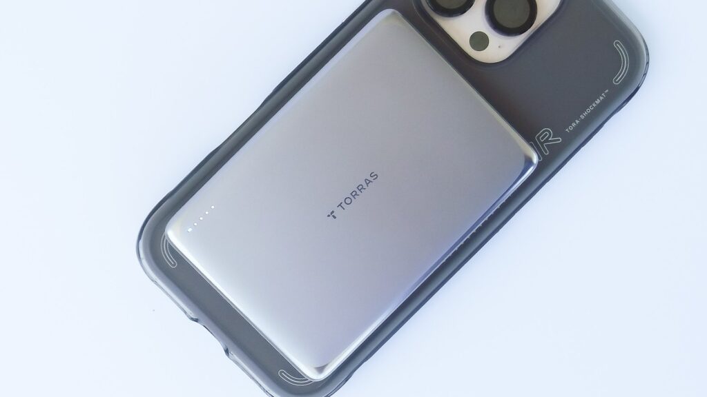 iPhone のケース背面に MiniMag Pro をMagSafeで取り付けた様子。バッテリーがiPhone本体より一回り小さく、ポケット運用しやすいサイズ感が分かる。