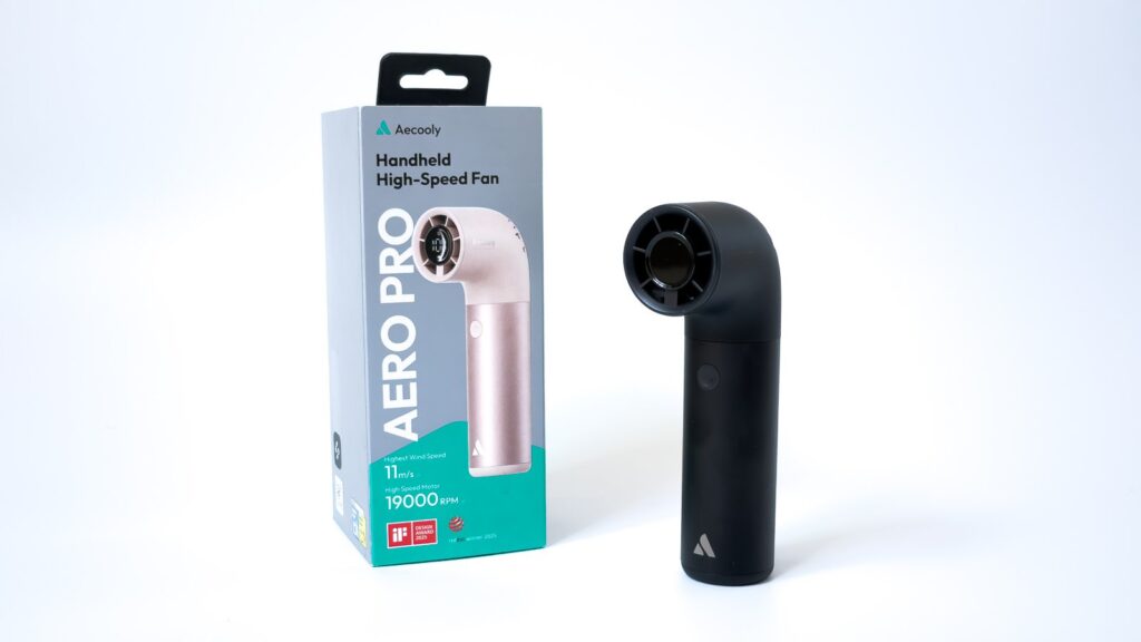 AERO PROハンディファンの黒い実機とパッケージを並べた構図で、本体はカーブした首部と円形の吹出口を持ち、箱にはピンクの本体写真と11m/s、19000RPMの表記がある。