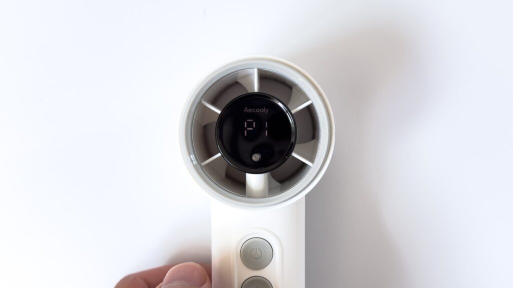 COLD AIRの送風口中央の液晶に風量表示「P1」が点灯した状態を正面から捉えた様子。Aecoolyのロゴと放射状のファンブレードが見え、柄の電源ボタンも写っている。