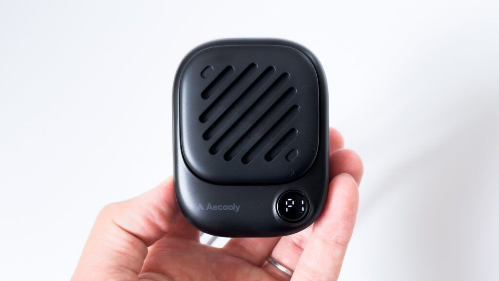 黒のネックファンを手前から見たアップ。斜めスリットの吹出口の下にAecoolyロゴと丸い液晶があり、液晶には風量を示す「F1」の白い表示が点灯している。