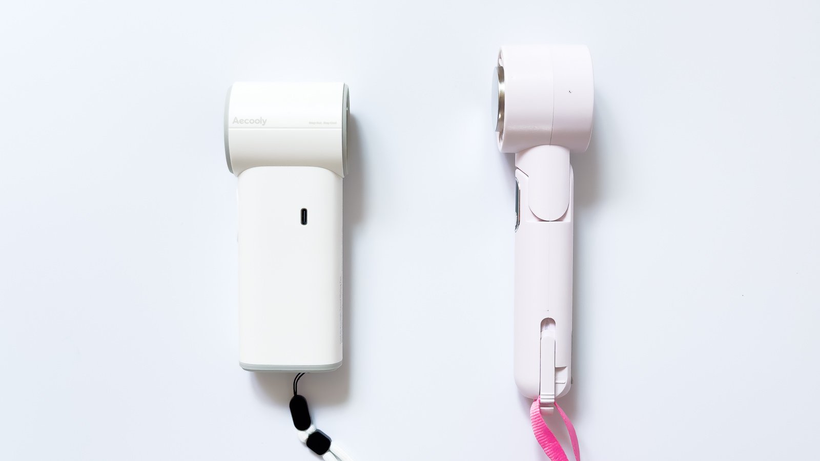 白いミストファンとピンクのハンディファンを並べて比較。左の本体には円筒形の送風部とUSB-C端子、右はファン部に丸い保護シールが貼られピンクのストラップが付く。