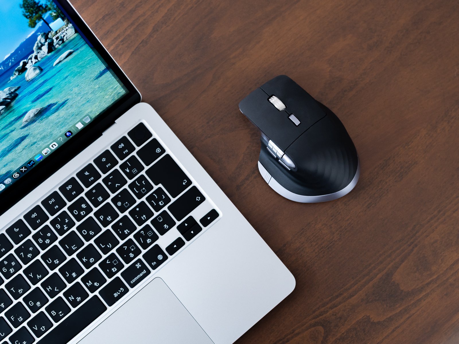 MacBookの画面を起こしたデスクを斜め上から写したカット。画面右のスペースに本体を置いている。