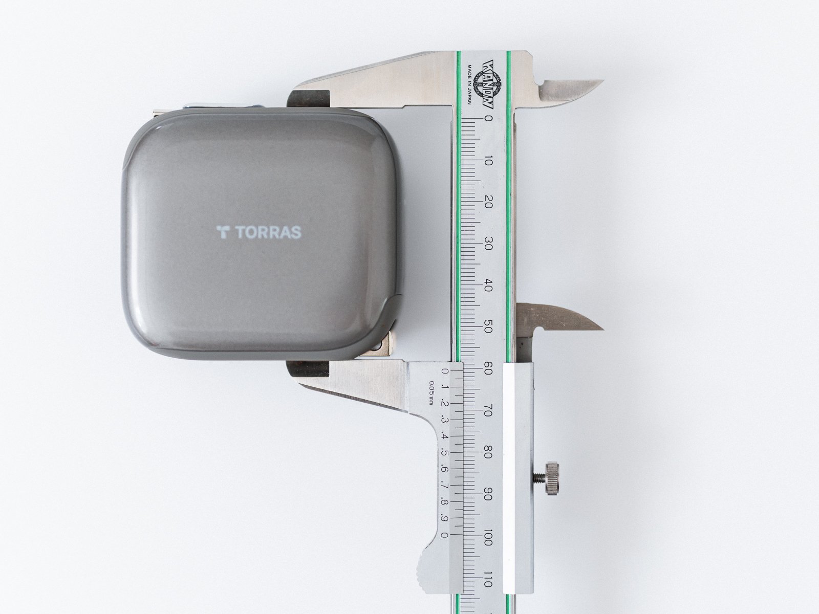 ノギスでTORRAS FlexLine Pro 60Wの縦方向の寸法を測定している状態。本体側面と測定器の目盛りが白い背景上に見える。