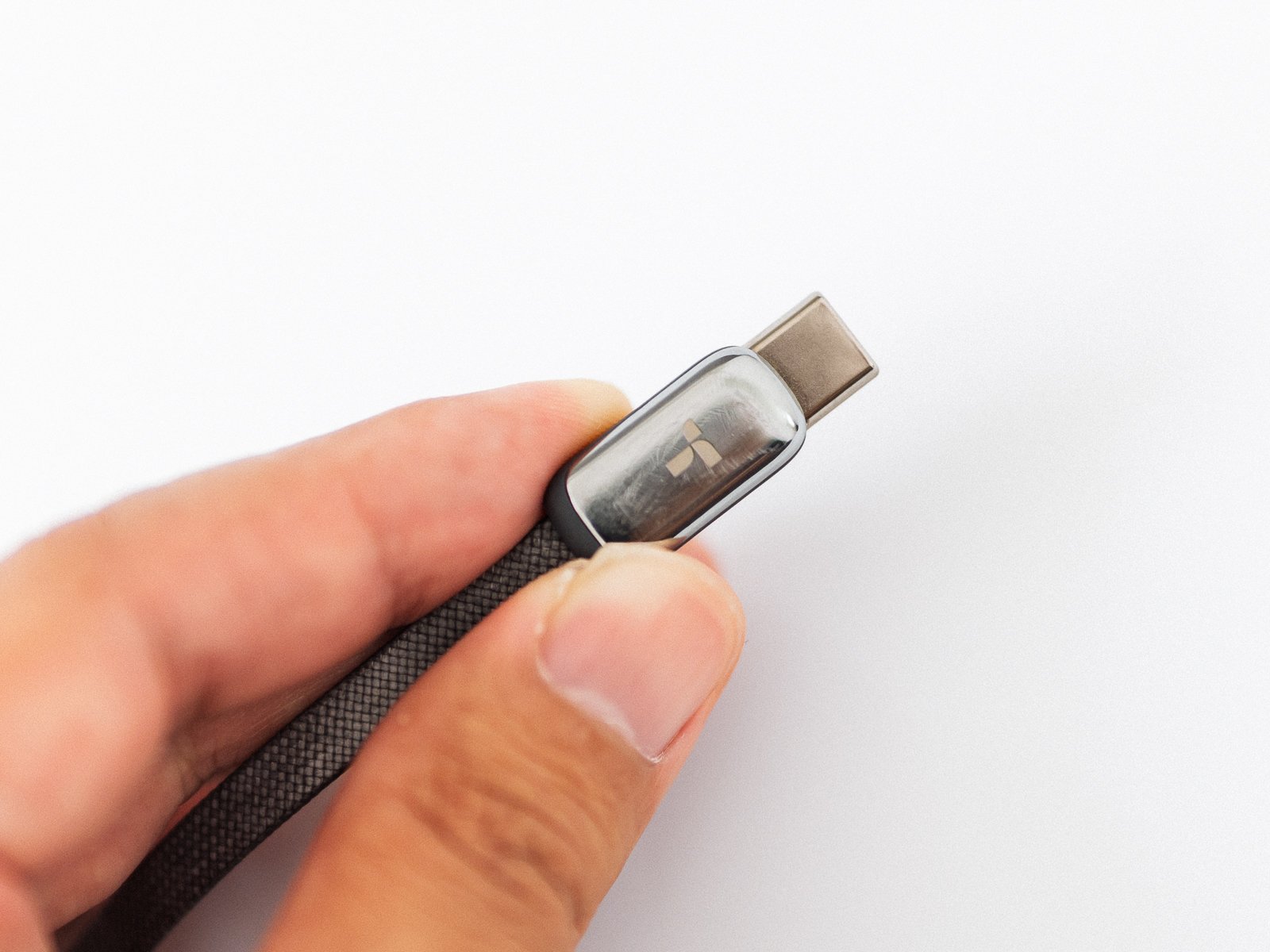 TORRAS FlexLine Pro 60Wの内蔵USB-C端子を指でつまんだ接写。透明感のある端子カバーと編み込み被覆のケーブルが見える。