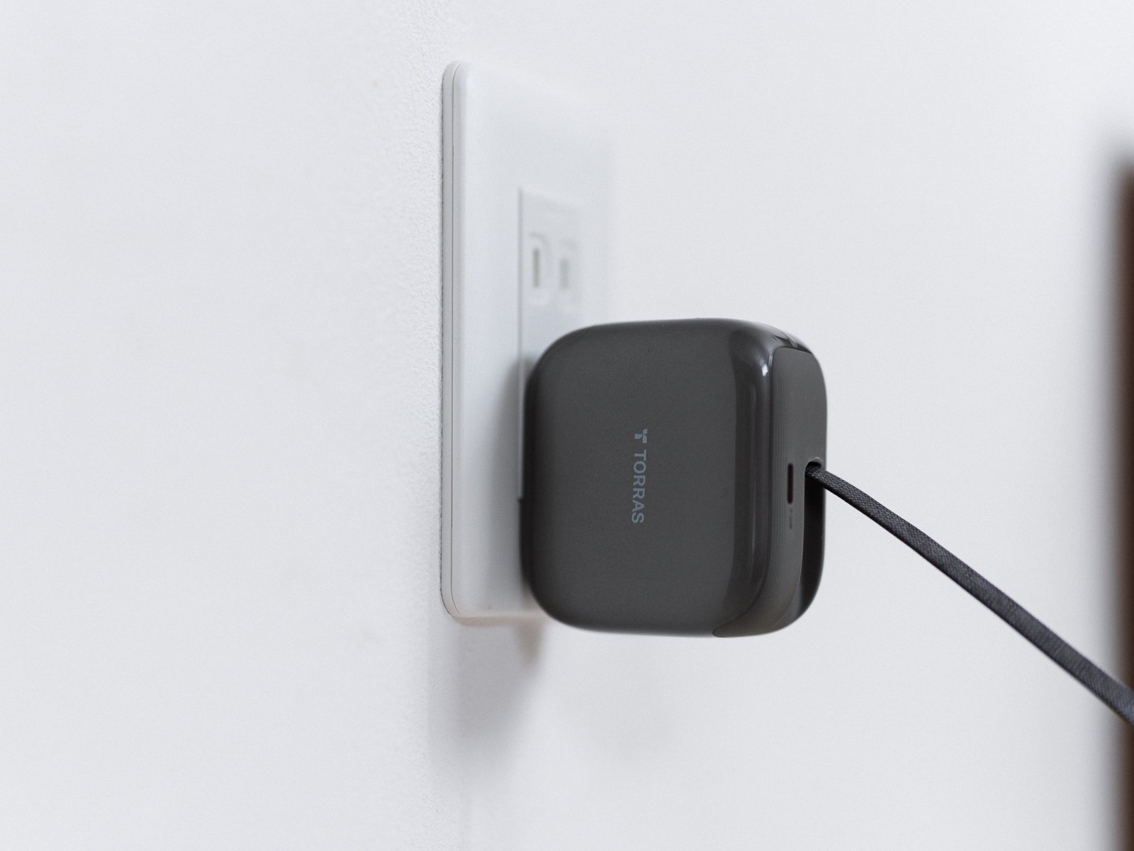 TORRAS FlexLine Pro 60Wを壁のコンセントに直接差し込み、内蔵USB-Cケーブルを下方向へ引き出している状態。