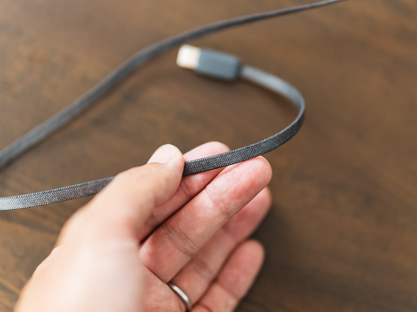 TORRAS FlexLine Pro 60Wの編み込み被覆ケーブルを手で持った接写。平たいケーブルの表面処理とUSB-C端子が確認できる。