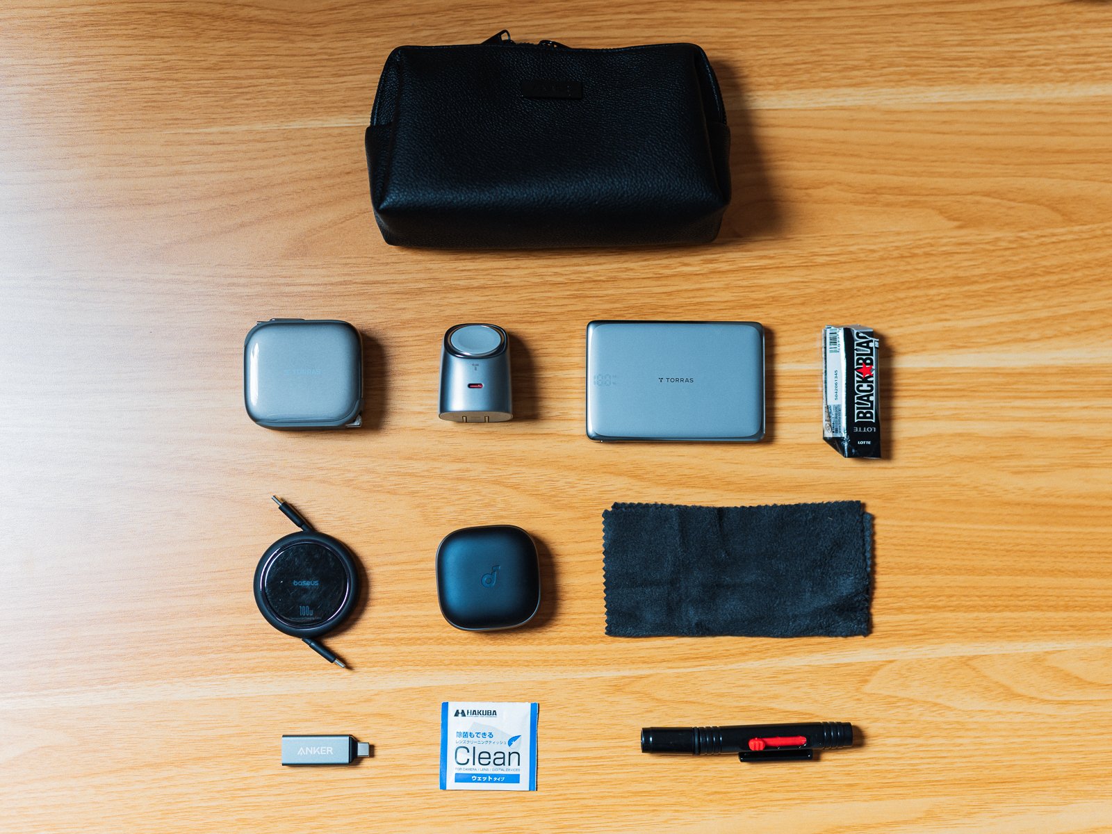 Anker Style Pouchと中身10点を真上から一覧にした状態。充電器、モバイルバッテリー、イヤホン、ケーブル、クロス、カードリーダー、ガムなどが並ぶ。