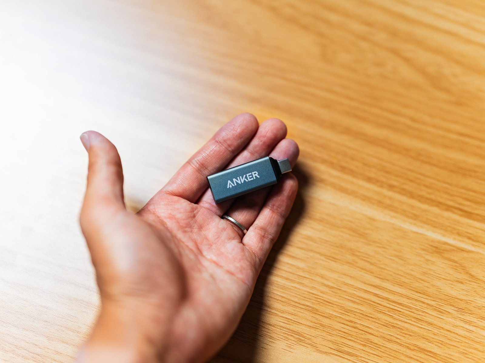 AnkerのUSB-C 2-in-1カードリーダーを手のひらに載せた状態。黒い小型本体のAnkerロゴとUSB-C端子が確認できる。