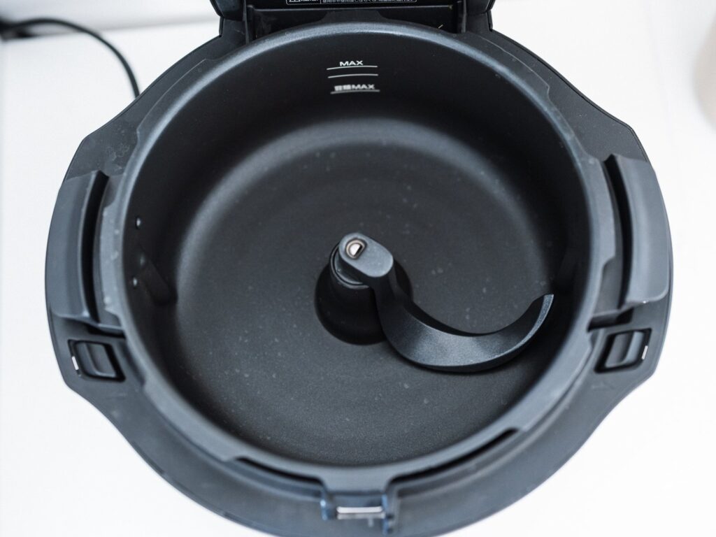 ふたを開けたオートクッカー NF-AC1000の内鍋を真上から見た様子。内側にMAXの目盛りがあり、中央にかきまぜ用の羽根が付いている。