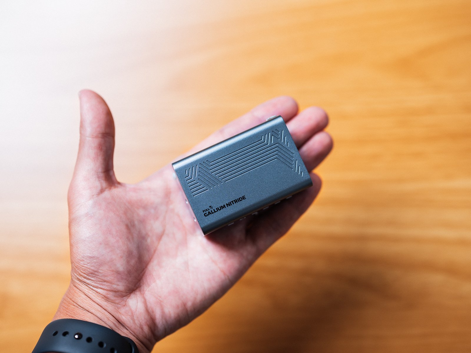 手のひらに載せたPHYSCE 67W GaN急速充電器。ウェッブグレーの本体は手のひらの中に収まる大きさで、側面に溝の模様が見える。