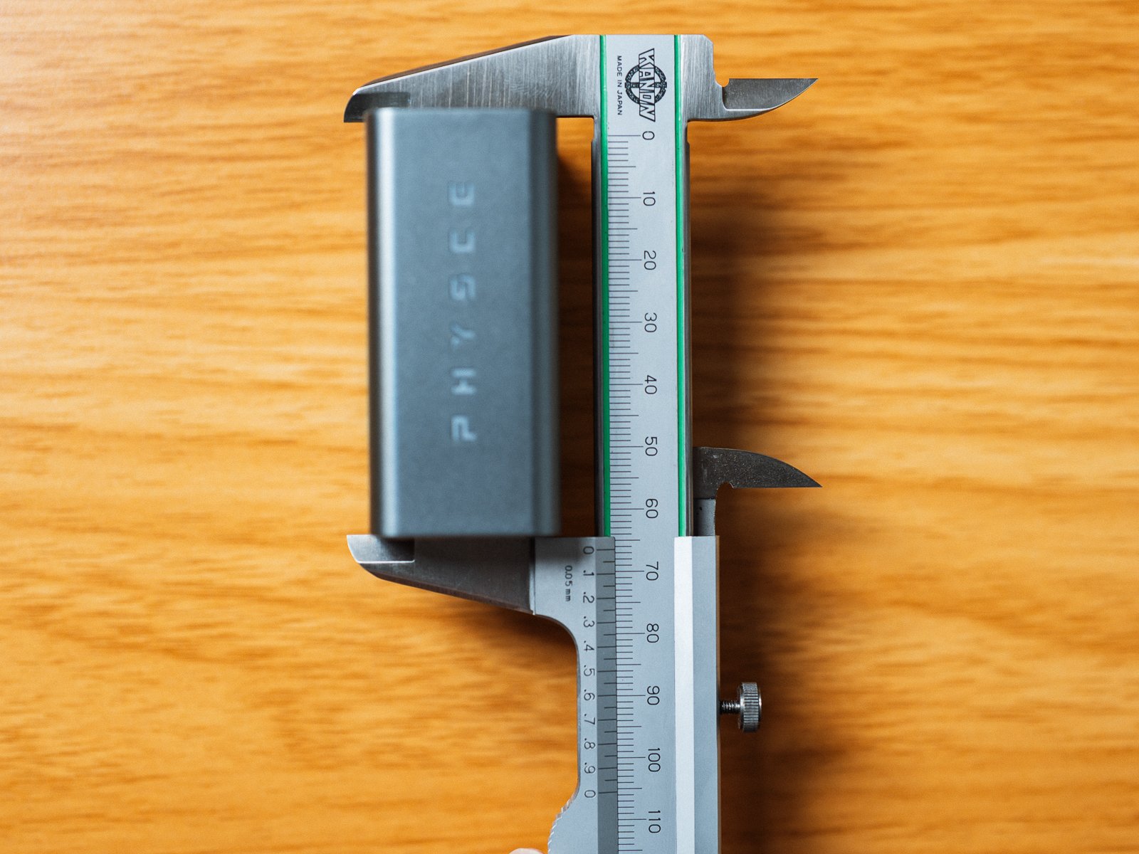 ノギスでPHYSCE 67W GaN急速充電器の奥行きを測っている様子。本体を挟んだノギスの目盛りは約66mmを示している。