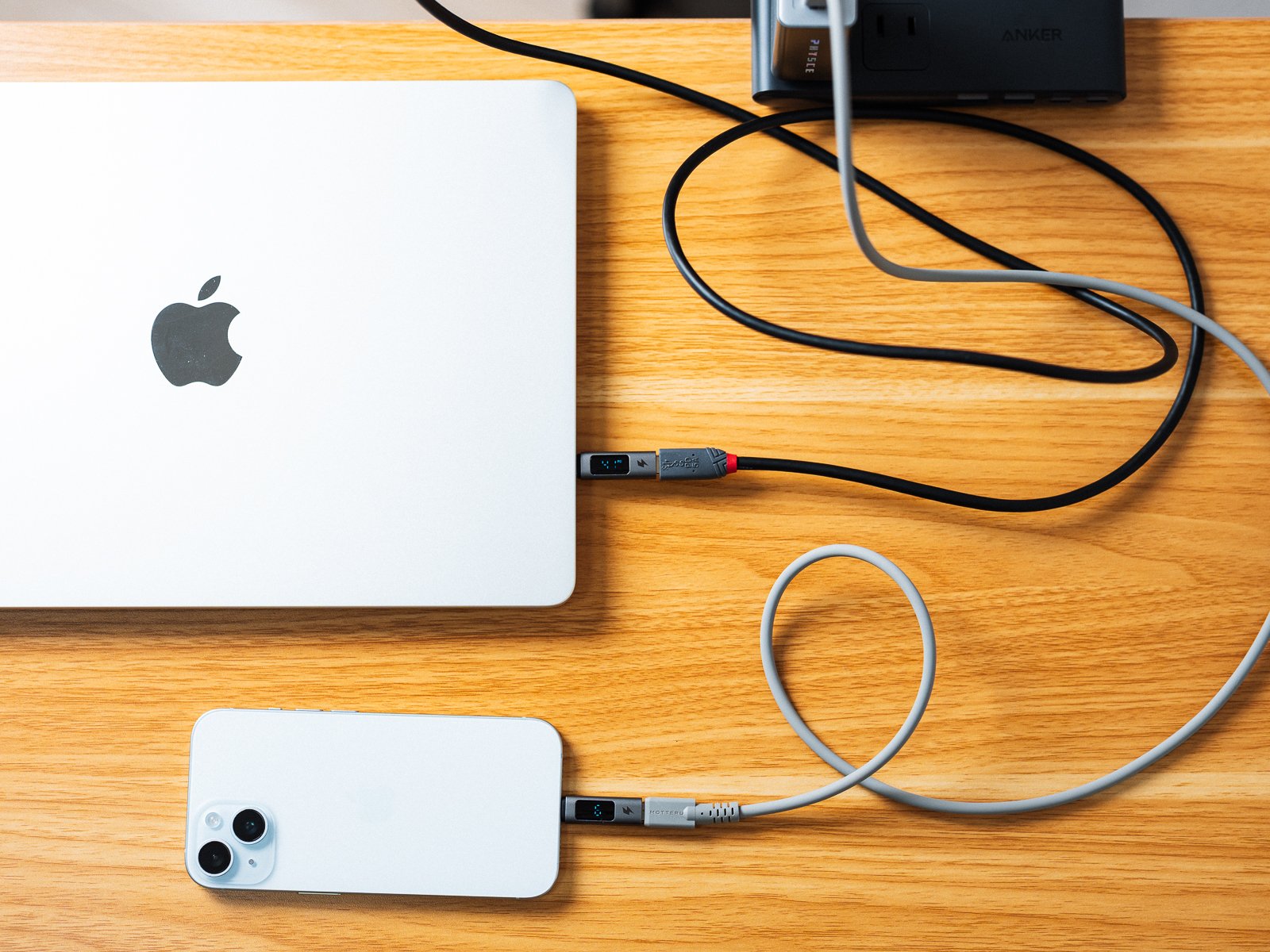 PHYSCE 67W GaN急速充電器からMacBook AirとiPhoneを2台同時に充電している様子。それぞれのケーブルの途中にワット数の表示部がある。