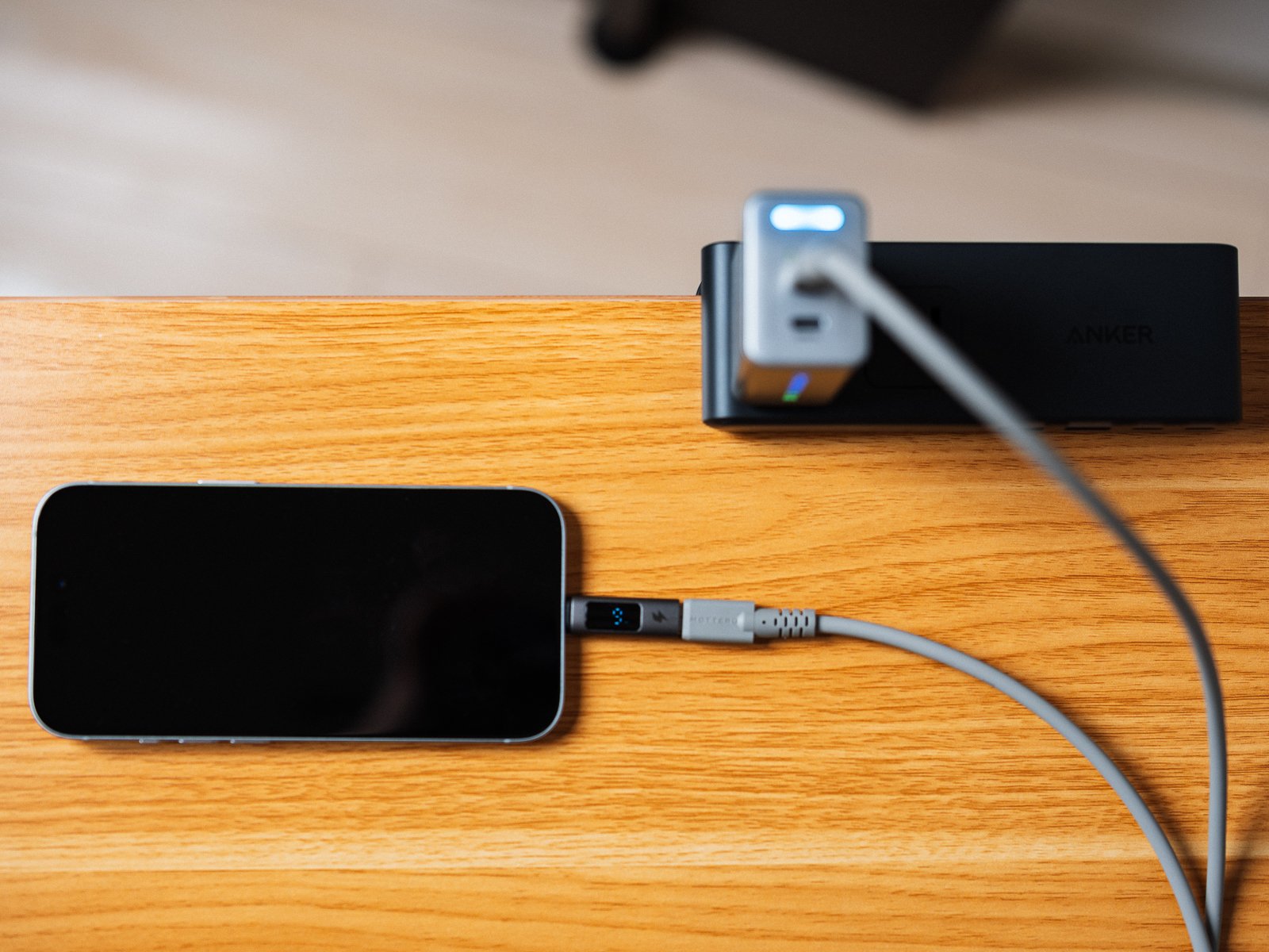 通常モードのPHYSCE 67W GaN急速充電器でiPhoneを充電している様子。天面のライトは青く光り、ケーブルの表示部にワット数が出ている。