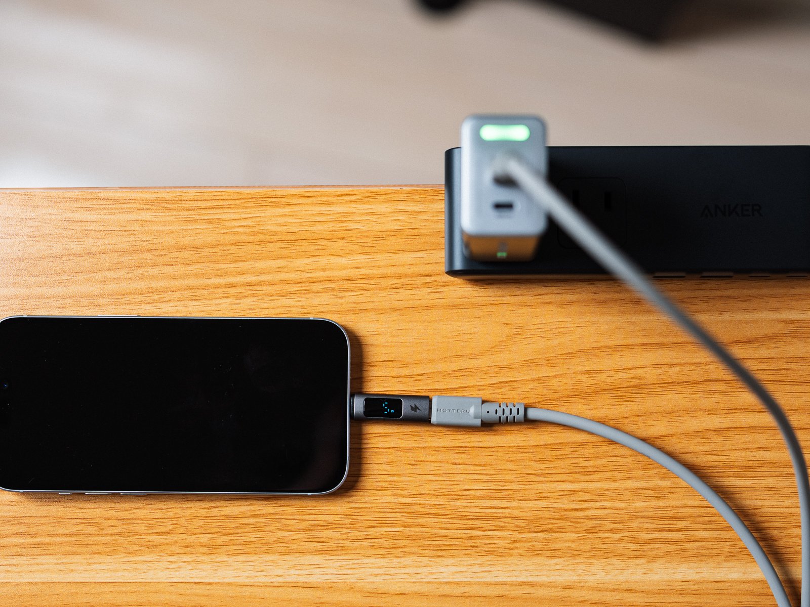 エコモードに切り替えたPHYSCE 67W GaN急速充電器でiPhoneを充電している様子。天面のライトは緑に光り、ケーブルの表示部にワット数が出ている。