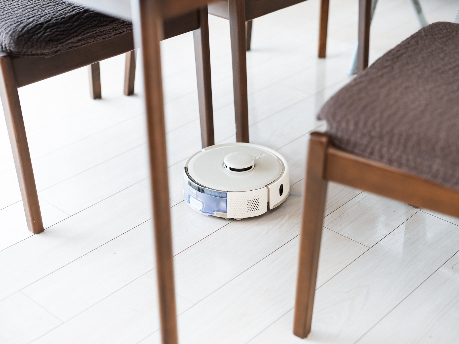 ダイニングテーブルの下で、イスの脚の間を掃除しているSwitchBot K11+ Pro