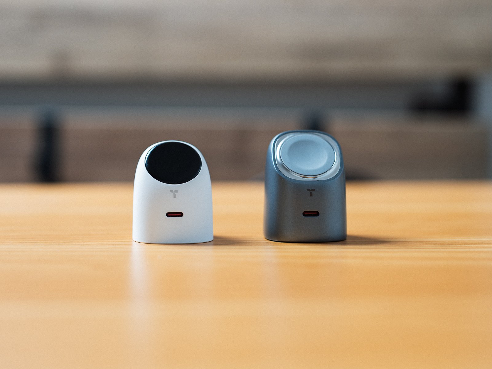 木製デスクに並べたTORRAS FlashEye Dotと前作のFlashEye。左が白いDot、右がグレーの前作で、前作は斜めの面がApple Watch用の充電パッドになっている。