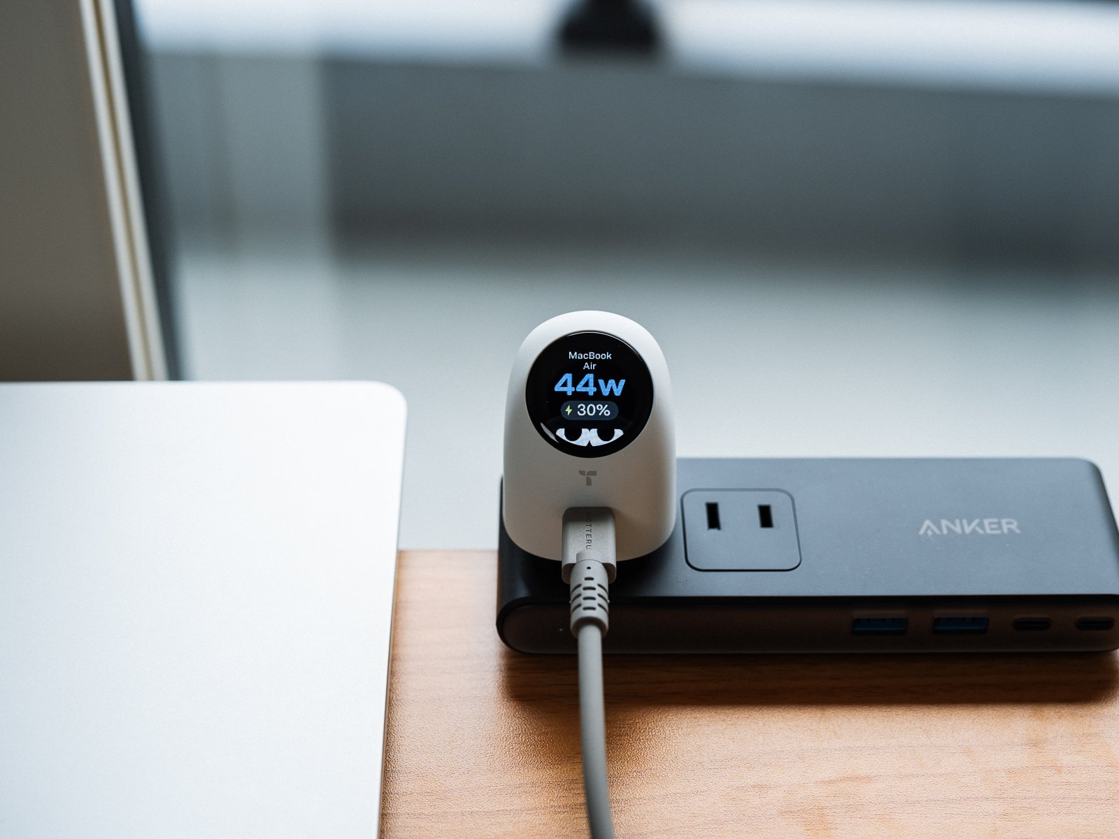 電源タップに挿したTORRAS FlashEye Dotでノートパソコンを充電している様子。丸い画面に「MacBook Air」、出力44W、バッテリー残量30%が表示されている。